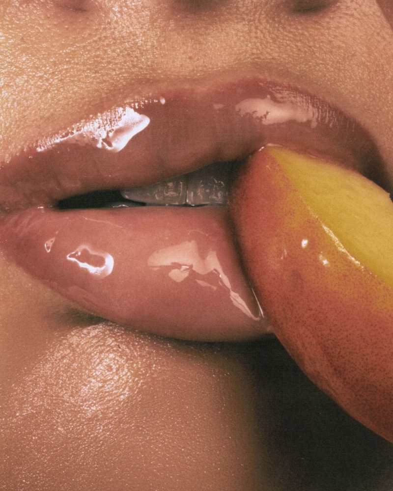 Glossy lips biting into a slice of peach